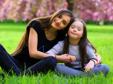 young woman and child with disability smiling