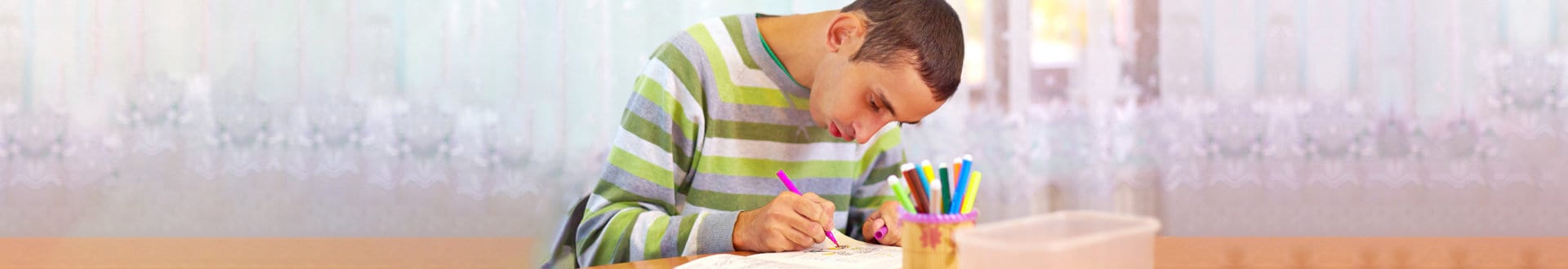 mentally challenge young man drawing on the table